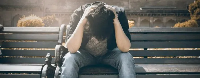 man crying on a bench