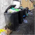 overflowing rubbish black wheelie bins on residential street