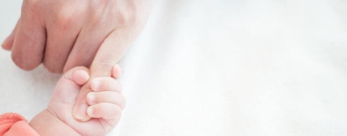 holding hands with newborn baby